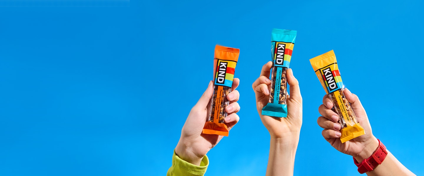 KIND snack bars held against a blue background